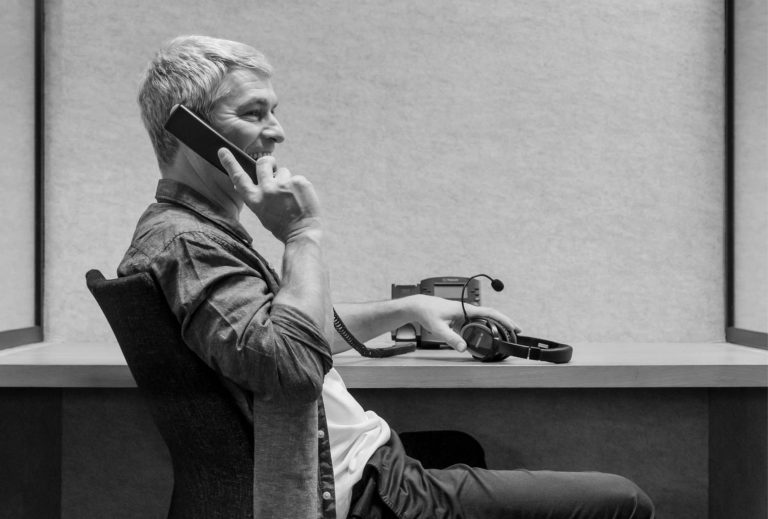 Hombre hablando por teléfono con auriculares Pronounce en su mano derecha